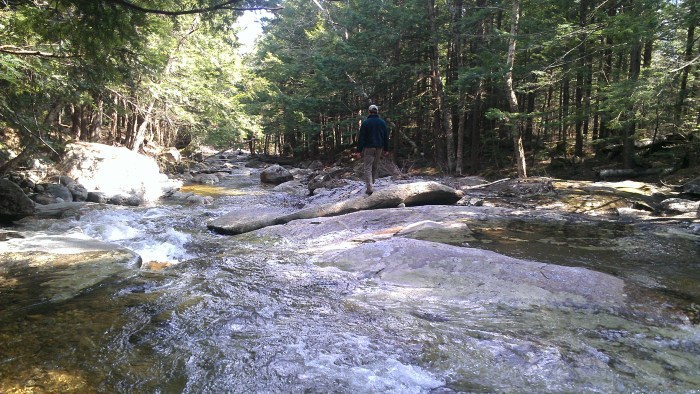 Andrew rock hops out to the middle of the river.